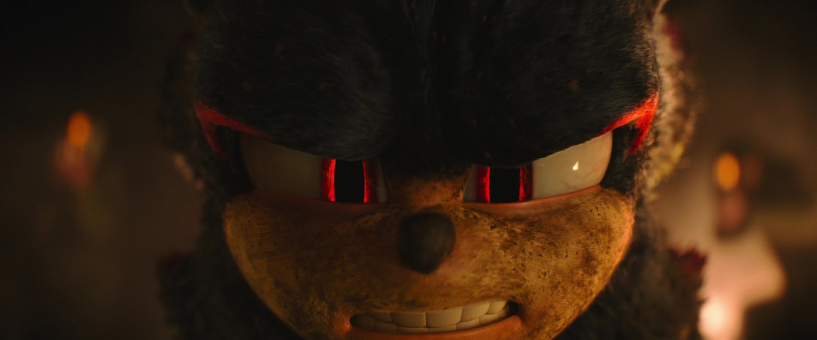 Sonic the Hedgehog 3 film still: extreme close-up of Shadow the Hedgehog's face in firelight, red eyes narrowed, wearing a confident and slightly menacing grin
